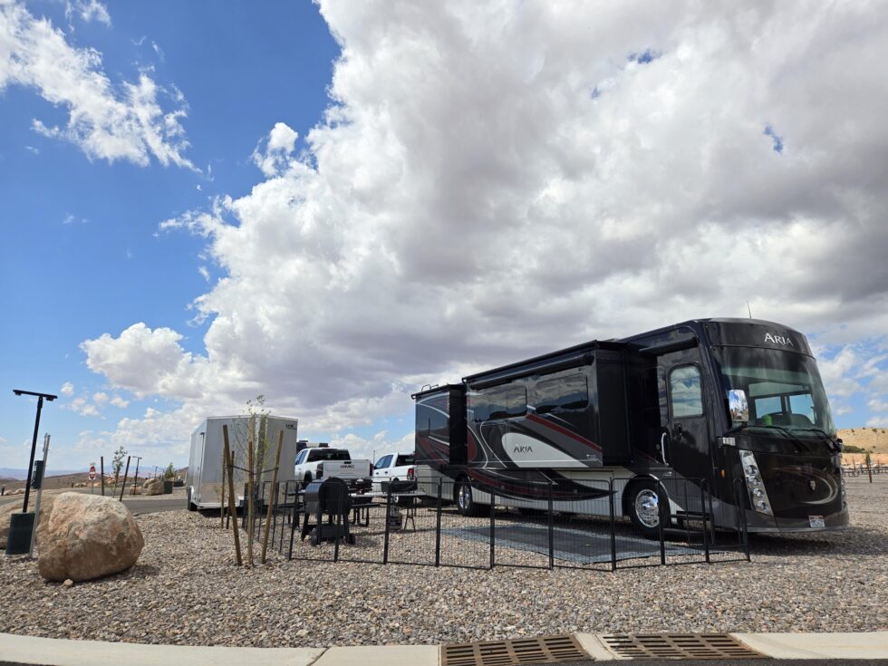 Motorhome on a gravel RV site with a picnic table and room outside
