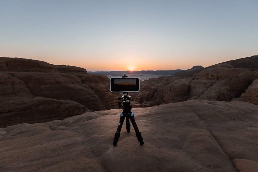A camera on a tripod set up to take a picture of the Southern Utah sunset across red rock.